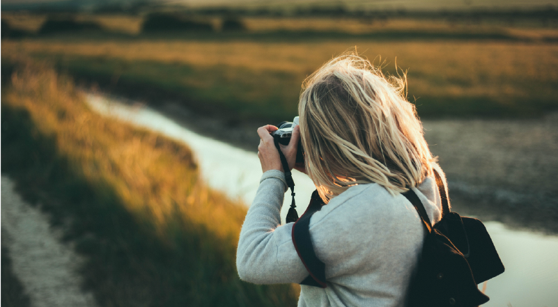 Woman shooting landscape scene with DSLR camera