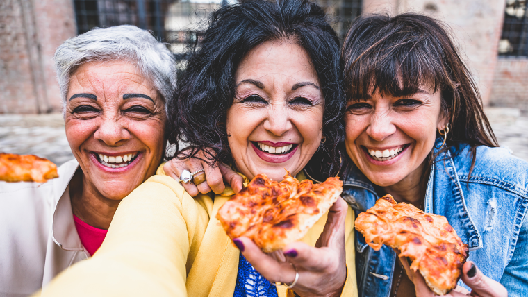 Women smiling and holding pizza