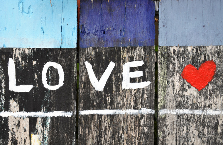 Wooden fence painted with word "love" and a red heart